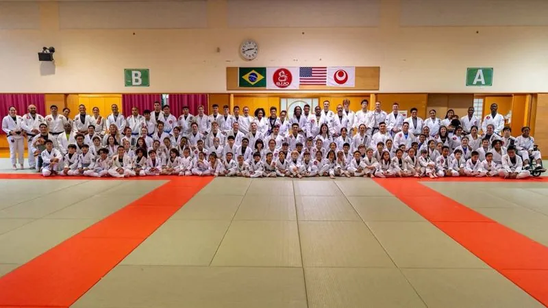 Full team photo, adults and kids, under four flags